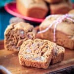 Slice of vegan date bread in front of the loaf on a serving board.