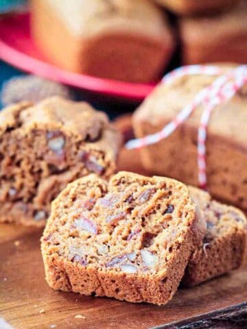 Slice of vegan date bread in front of the loaf on a serving board.