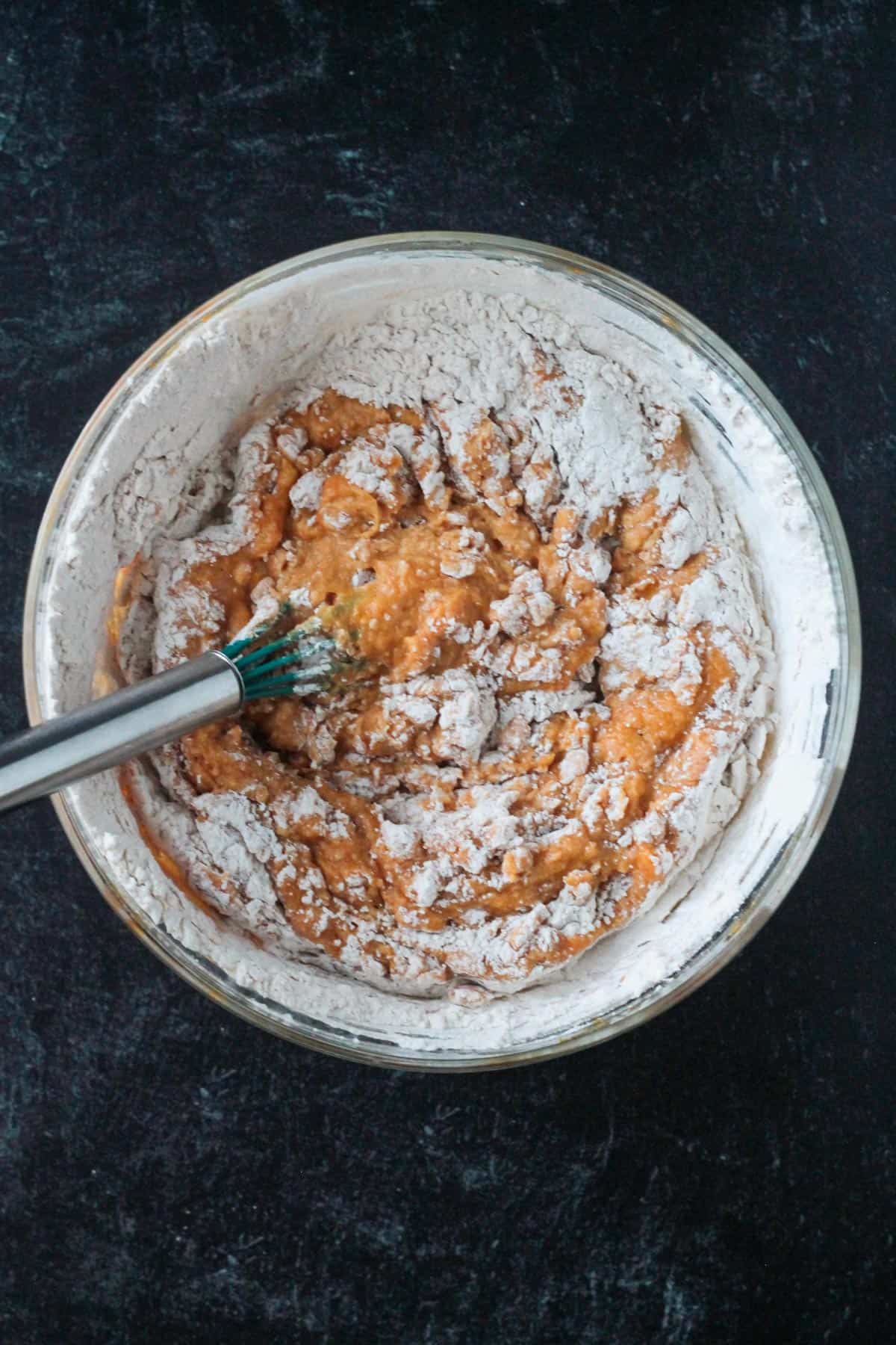 Whisking the dry and wet ingredients together in a bowl.