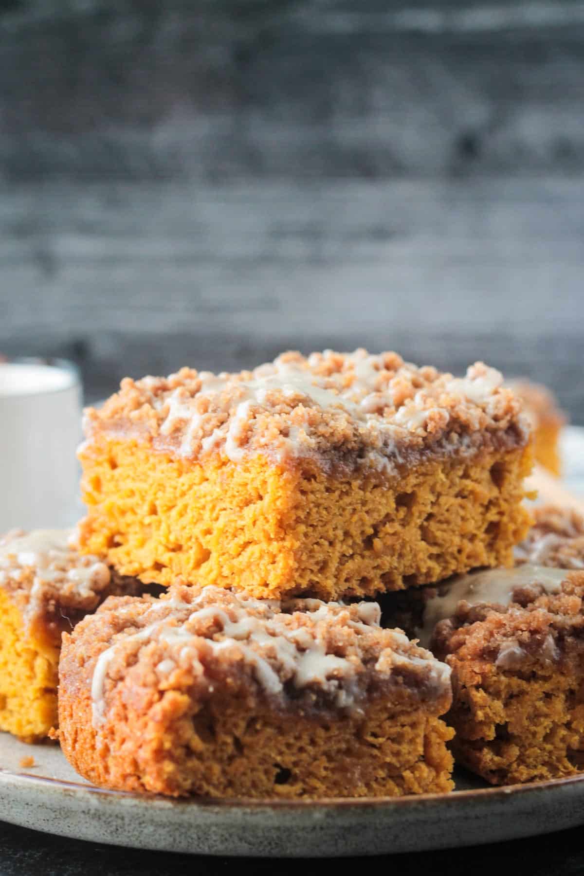 Slices of pumpkin coffee cake stacked in a pile on a plate.
