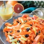 Carrot pineapple salad with dried cranberries on a gray plate.