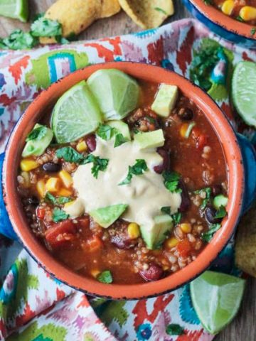 Taco Chili in a blue bowl topped with vegan ranch, cilantro, and lime wedges.