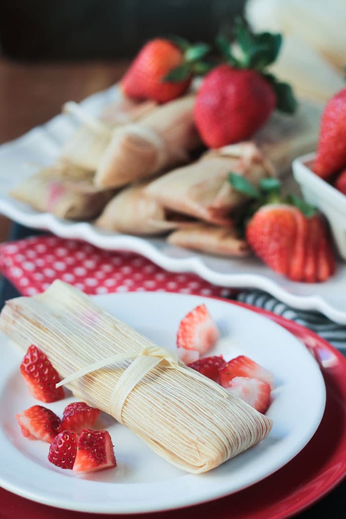 Vegan dessert tamale on a plate with fresh chopped strawberries.