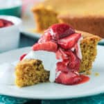 Vanilla cornbread cake topped with strawberries and whipped cream.