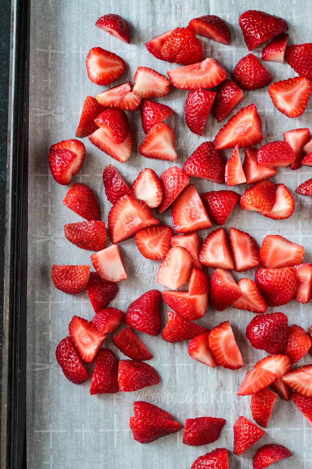 Fresh sliced strawberries on a baking sheet.