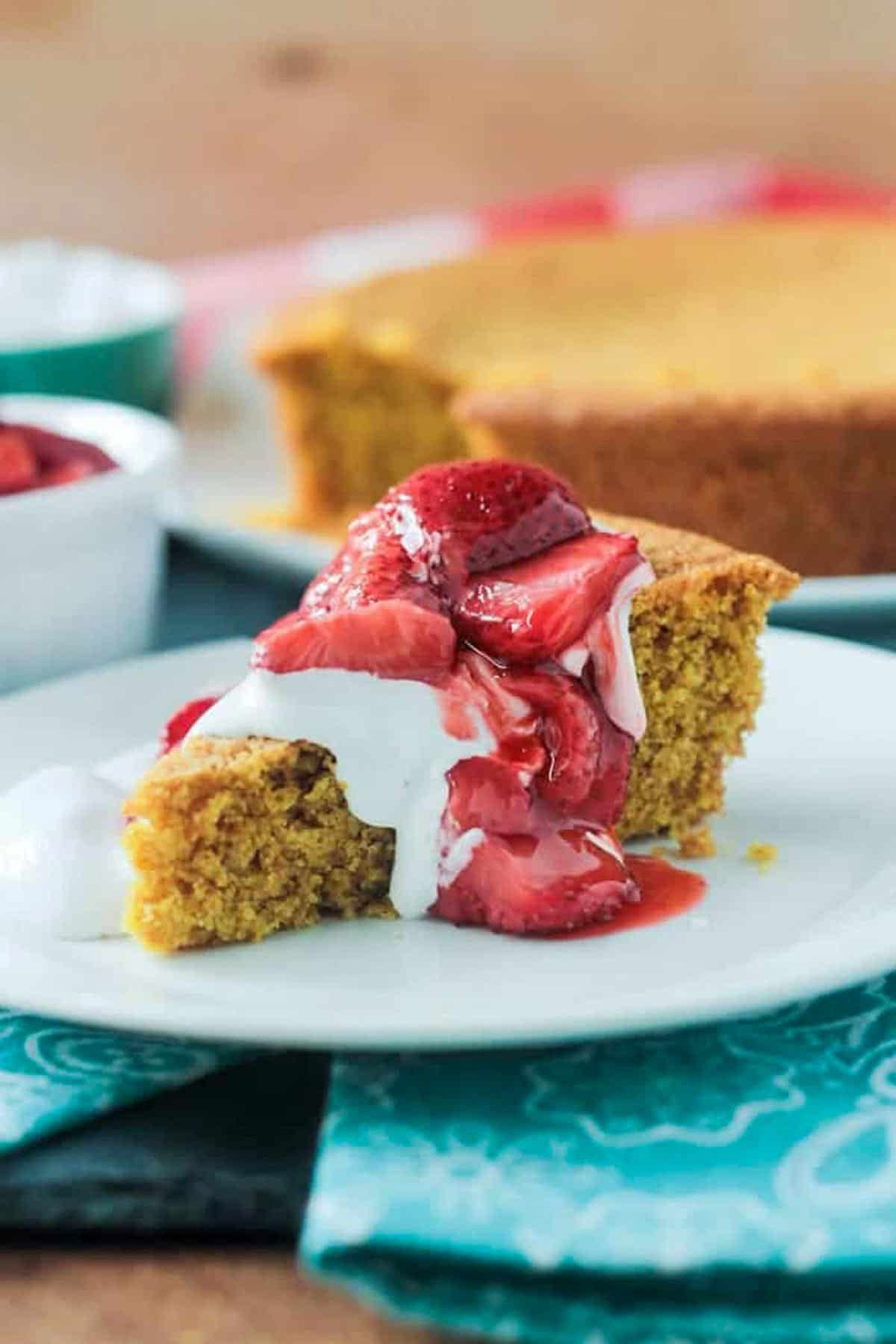 Vanilla cornbread cake topped with strawberries and whipped cream.