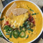 Two tortilla chips dipped in a bowl of creamy cashew queso.