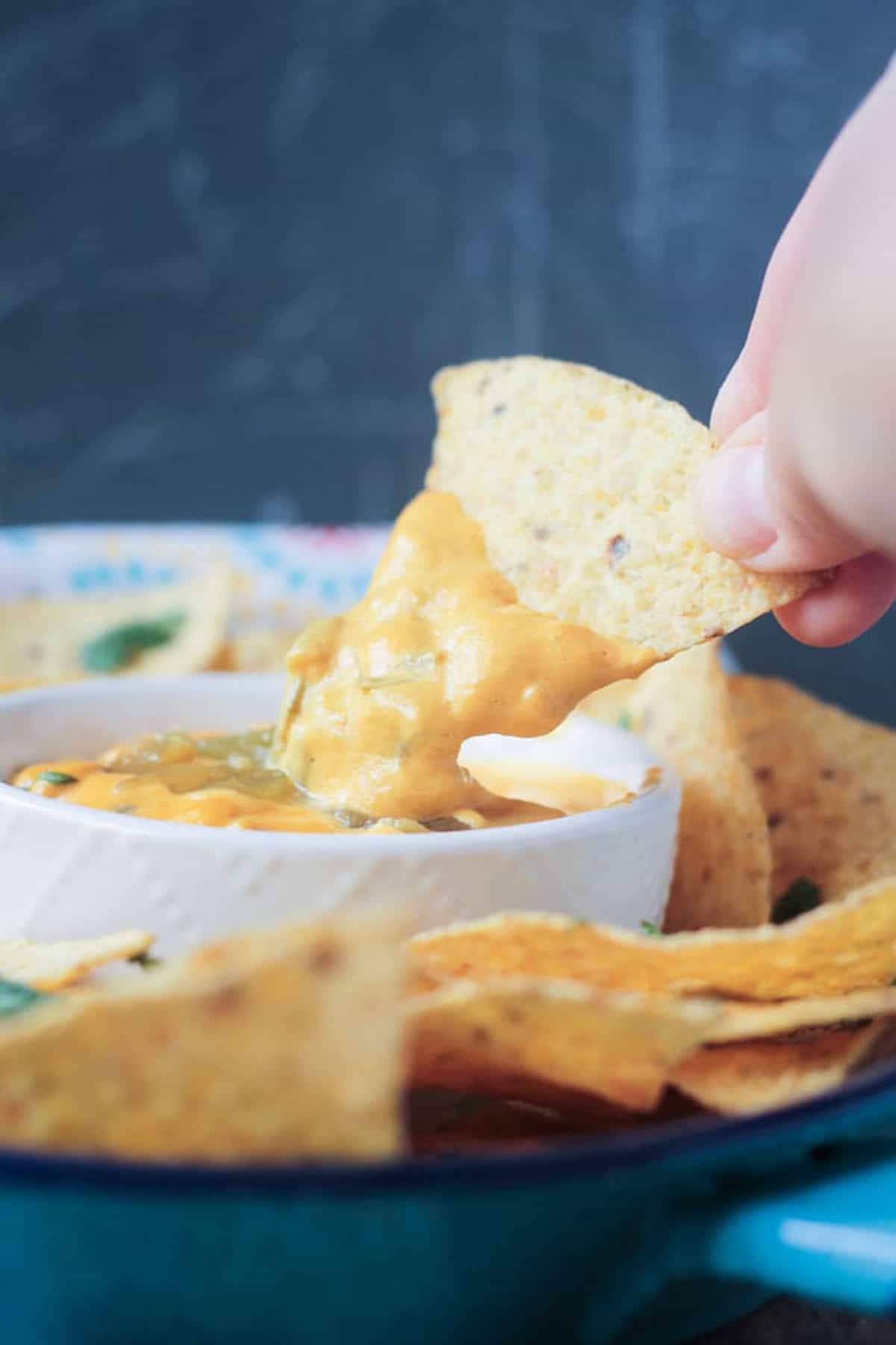 tortilla chip being dipped into a bowl of cheese dip