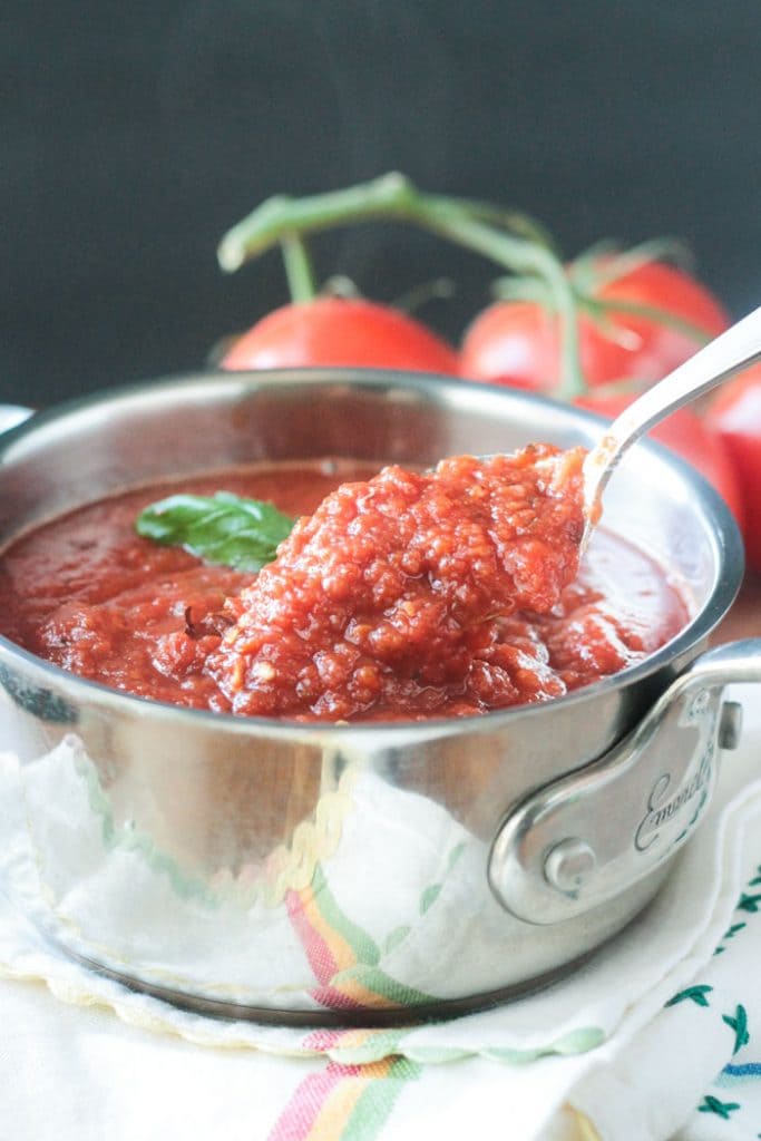 A spoonful of sauce being lifted out of the pot of Spicy Marinara.