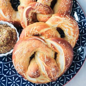 Pile of soft baked pretzels on a blue plate.