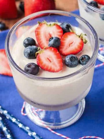 Vegan vanilla pudding in a glass bowl topped with fresh berries.