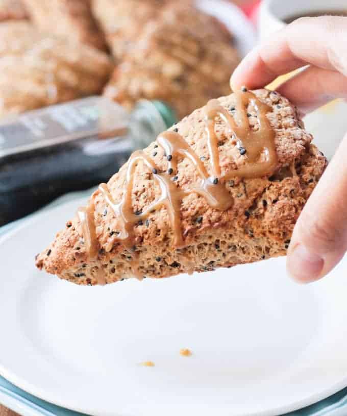 Hand holding a Banana Black Sesame Vegan Scones with Maple Tahini Glaze.