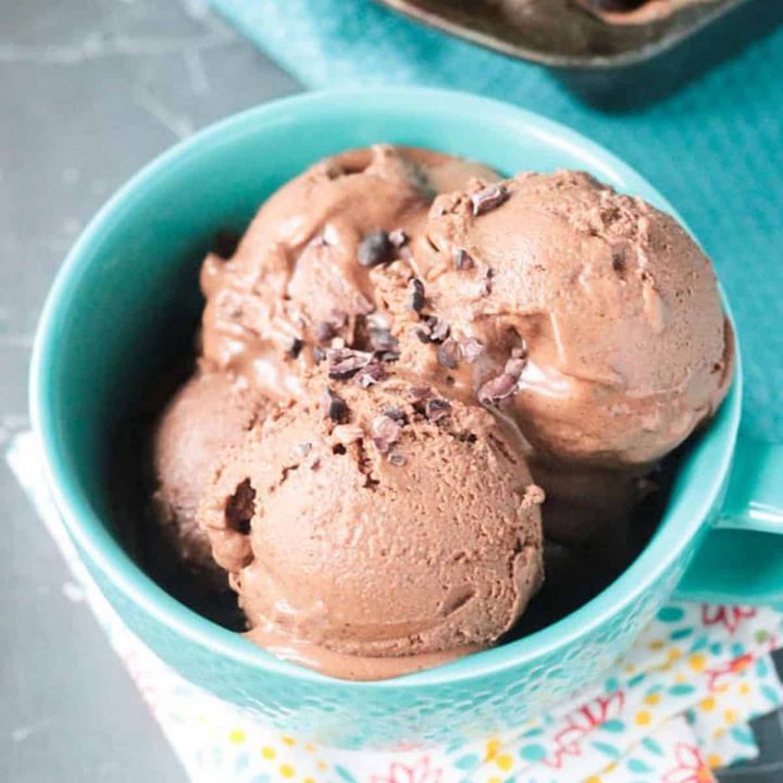 3 scoops of homemade chocolate ice cream in a blue bowl topped with cacao nibs.