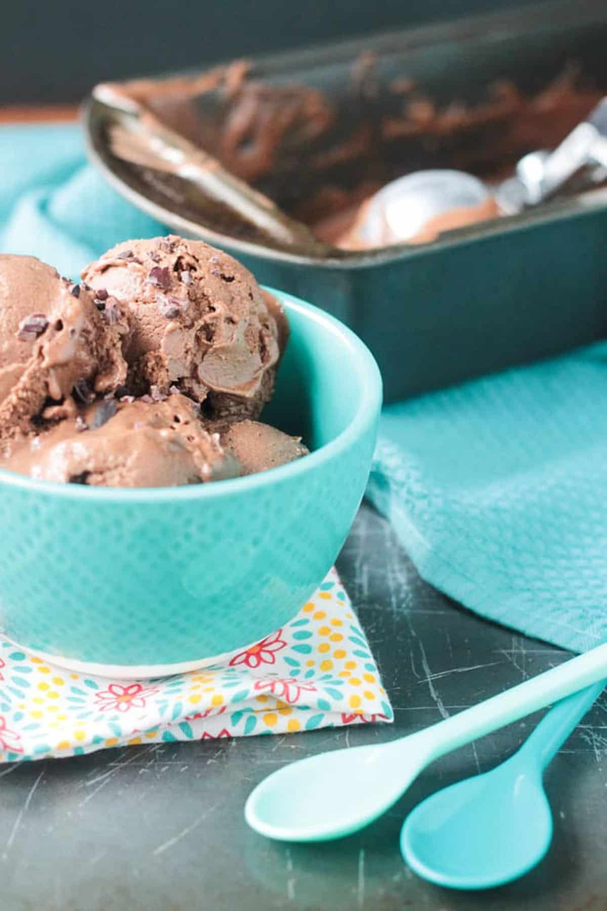 two blue spoons lying next to a bowl with a container in the background