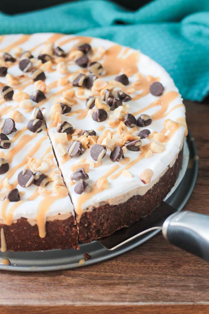 Frozen Chocolate chip peanut butter pie, with one slice cut, topped with chocolate chips and caramel drizzle.