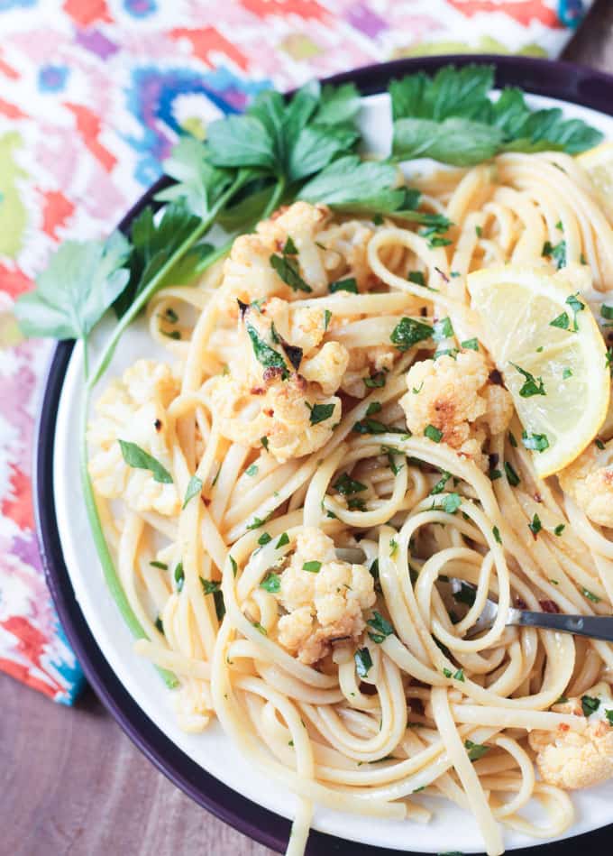 Plate of linguine with roasted cauliflower, lemon wedges, and parsley.