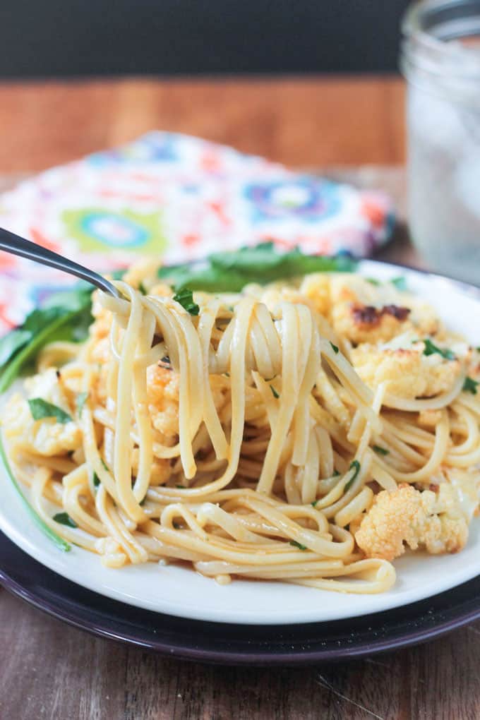 Fork twirling linguine noodles over a plate of pasta.