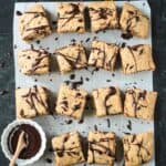 Squares of chocolate chip zucchini cake drizzled in chocolate sauce.