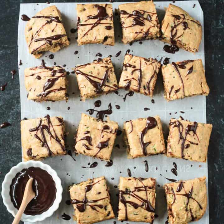 Squares of chocolate chip zucchini cake drizzled in chocolate sauce.