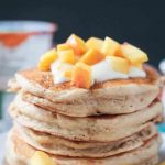 Close up photo of a stack of 5 peach pancakes.