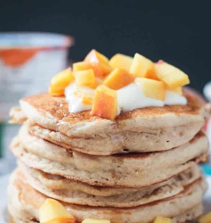 Close up photo of a stack of 5 peach pancakes.