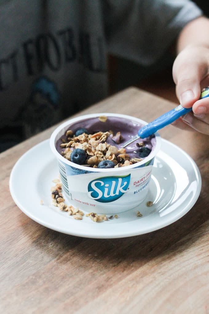 Container of Silk Blueberry yogurt topped with granola and fresh blueberries.
