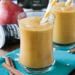 Pumpkin pear smoothie in a glass with an orange and white straw.