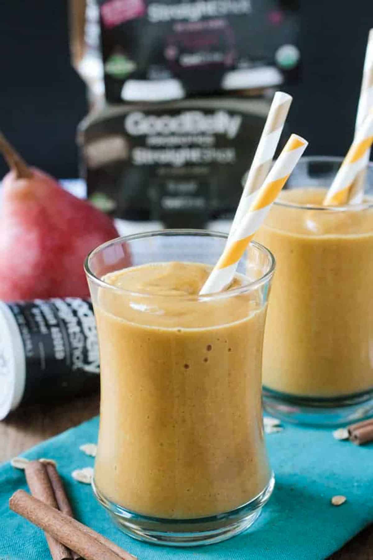 Probiotic Pumpkin Pear Smoothie - pumpkin, pears, warm fall spices, oats to keep you full, and a shot of Good Belly Probiotic to keep your tummy happy. Dairy Free, Vegan, and Refined Sugar Free. It's the autumn breakfast or snack. Pumpkin pear smoothie in a glass with an orange and white straw.