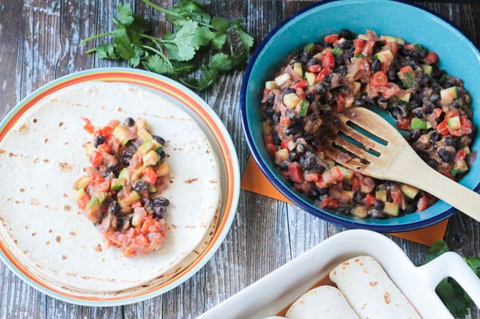 Black bean zucchini filling being spooned onto a tortilla.