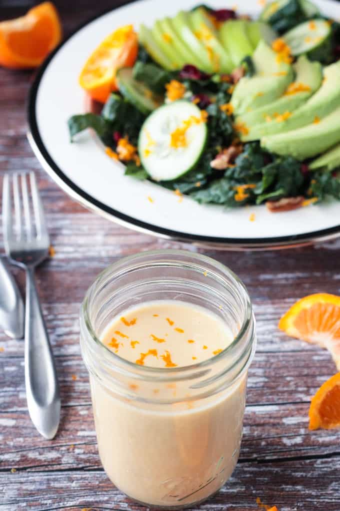 Jar of sauce in front of a kale salad.