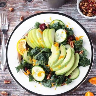 Overhead view of a kale salad with apples, avocados, cucumbers, and orange zest.