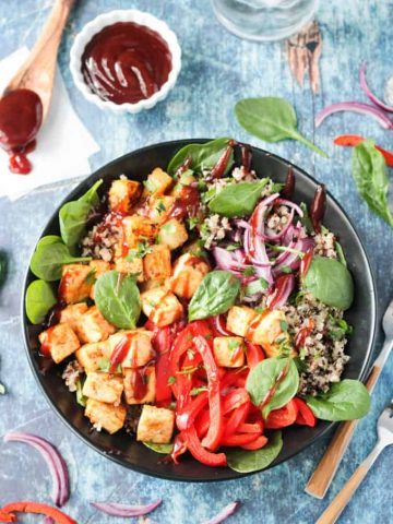 Overhead view of a BBQ Hawaiian Tofu Bowl w/ peppers, onions, pineapple, spinach, quinoa, and a drizzle of bbq sauce.