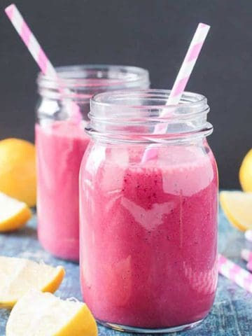 Two glasses of pink hued strawberry beet smoothie with straws.