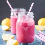 two glass jars of pink smoothie with straws in each