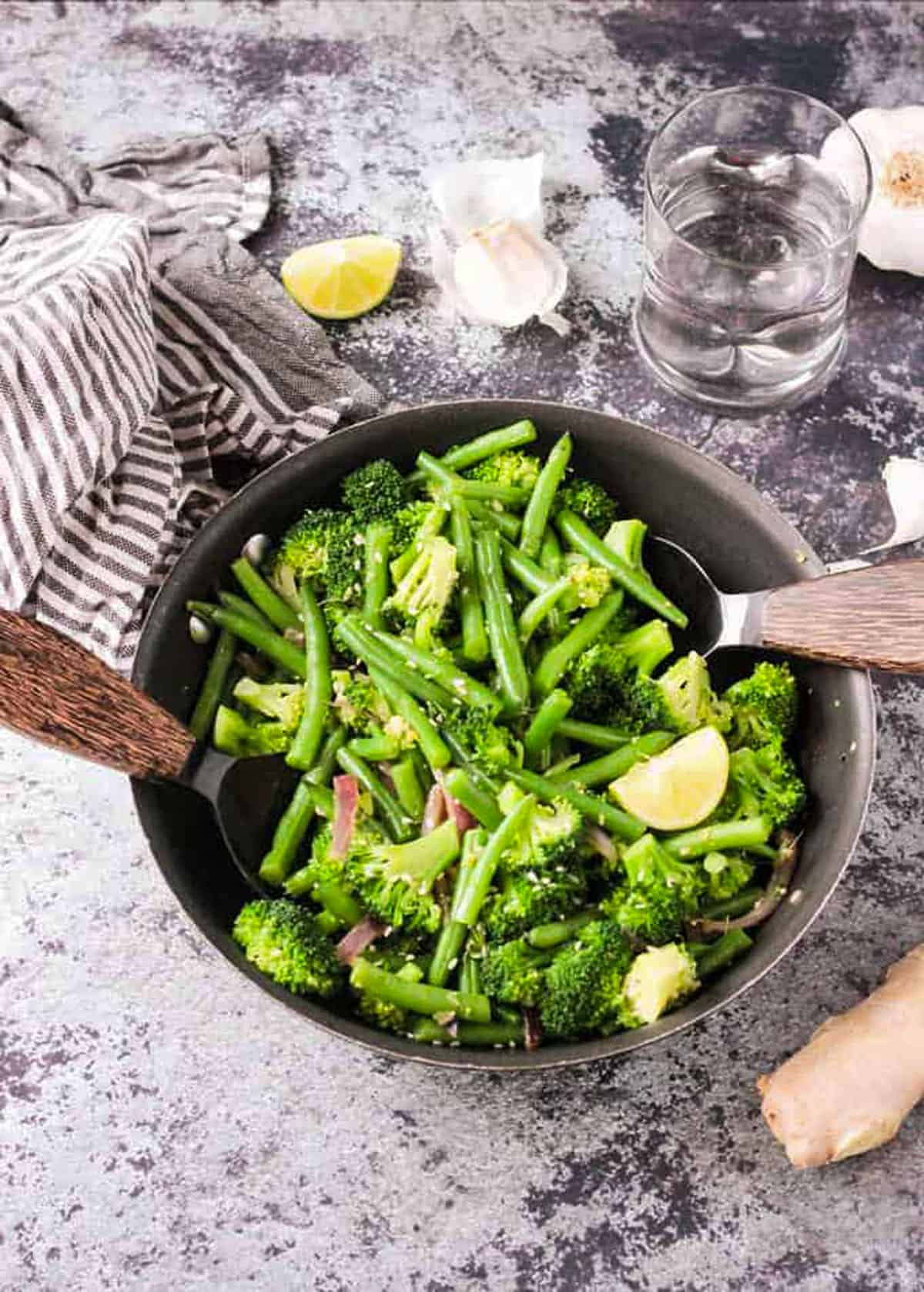 Easy Green Bean Broccoli Stir Fry. An easy weeknight vegetable side dish that takes less than 30 minutes. Just a few ingredients are needed, but it brings lots of flavor and nutrients. Serve it as a side or over pasta or rice. Broccoli, green beans, and red onion in a skillet with two serving spoons.