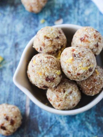 Overhead view of a bowl of Lemon Coconut Cashew Date Balls on a blue background