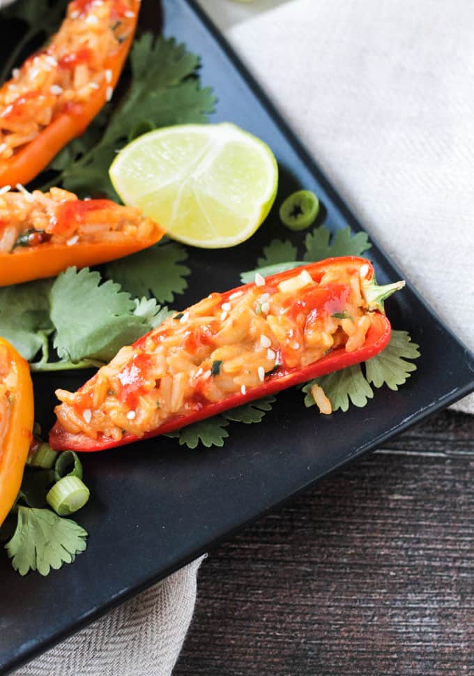 Overhead close up shot of a halved mini bell pepper stuffed with spicy peanut rice and drizzled with sriracha.