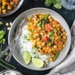 Vegan Thai green curry vegetables with chickpeas served with white rice and a lime wedge.