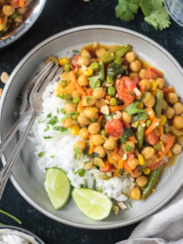 Vegan Thai green curry vegetables with chickpeas served with white rice and a lime wedge.