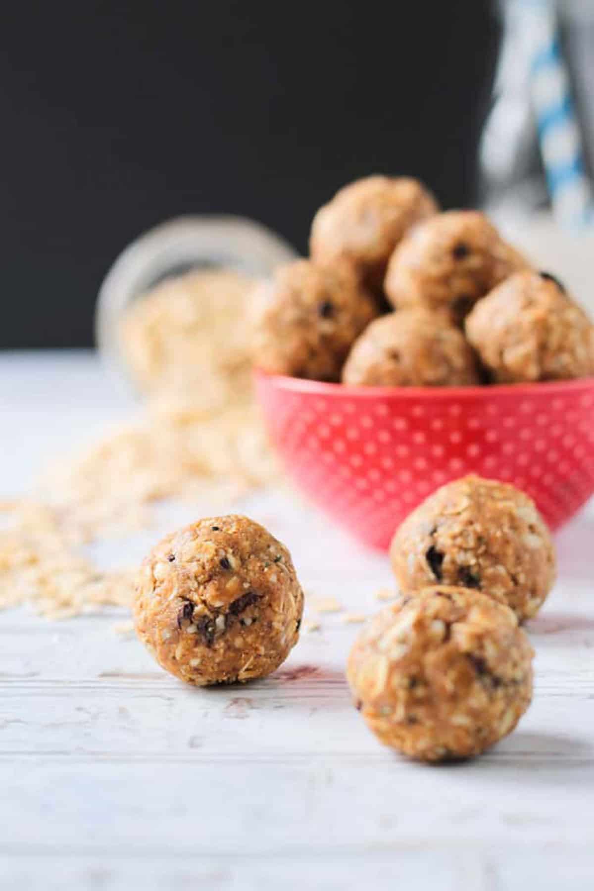 Close up of three protein balls in front of a red bowl.