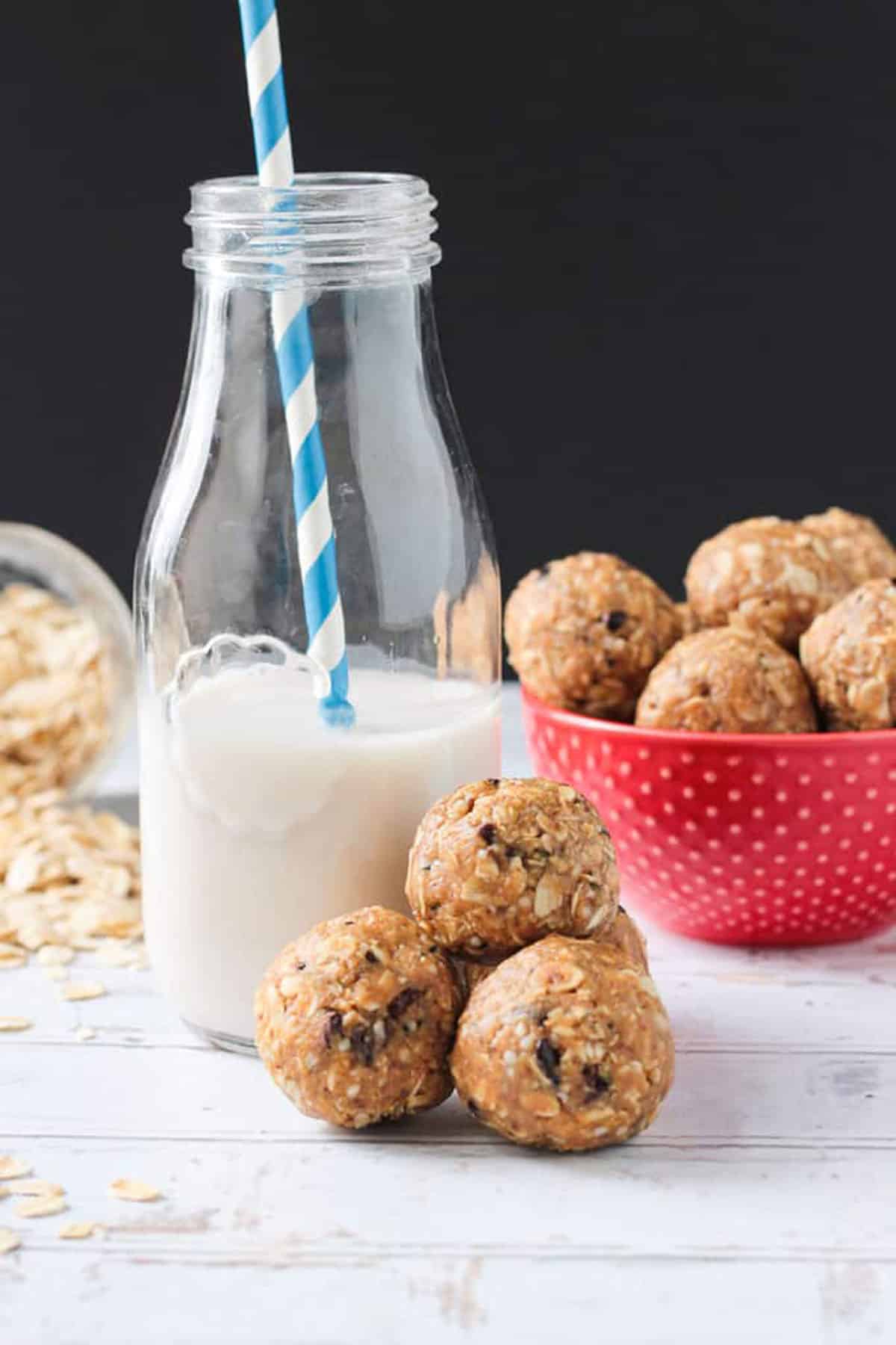 Three oatmeal peanut butter balls beside a glass of milk. 