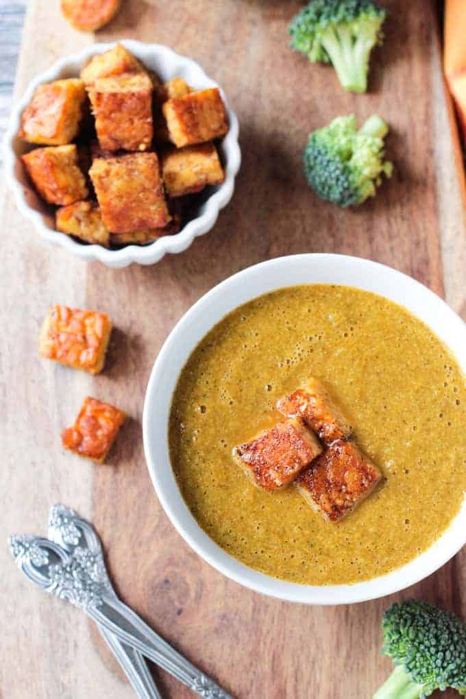 Overhead view of a bowl of vegan broccoli soup topped with three tempeh 