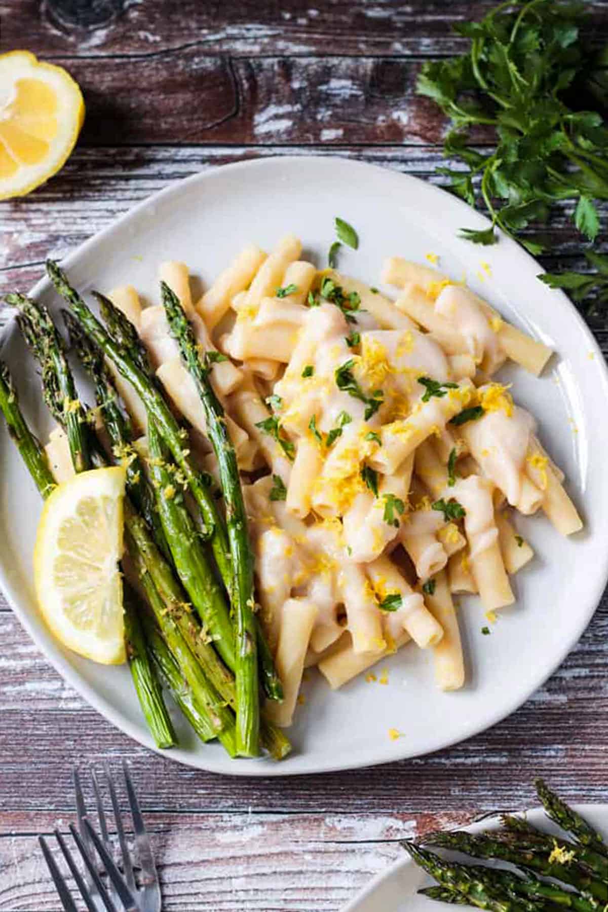 Creamy pasta on a white plate with a side of roasted asparagus.