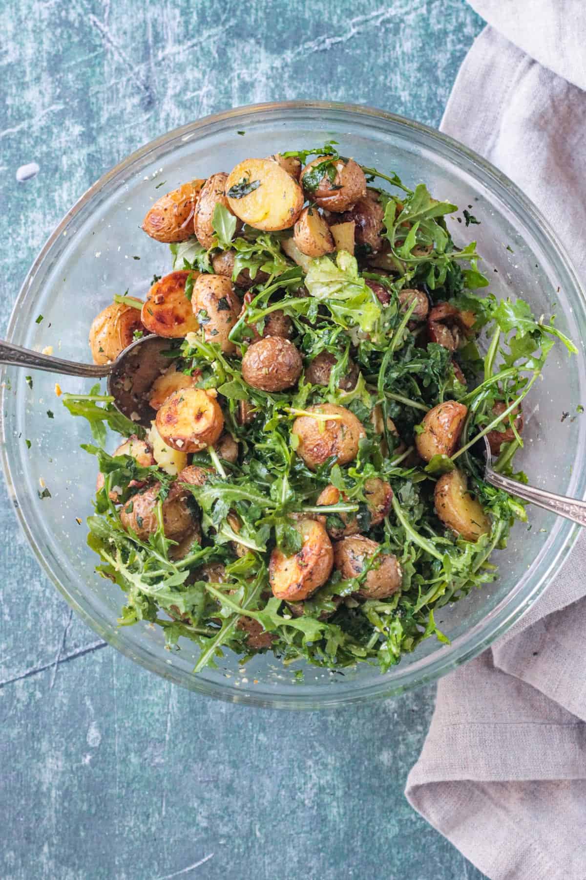 Arugula salad with herb roasted potatoes and vegan parmesan cheese tossed together.