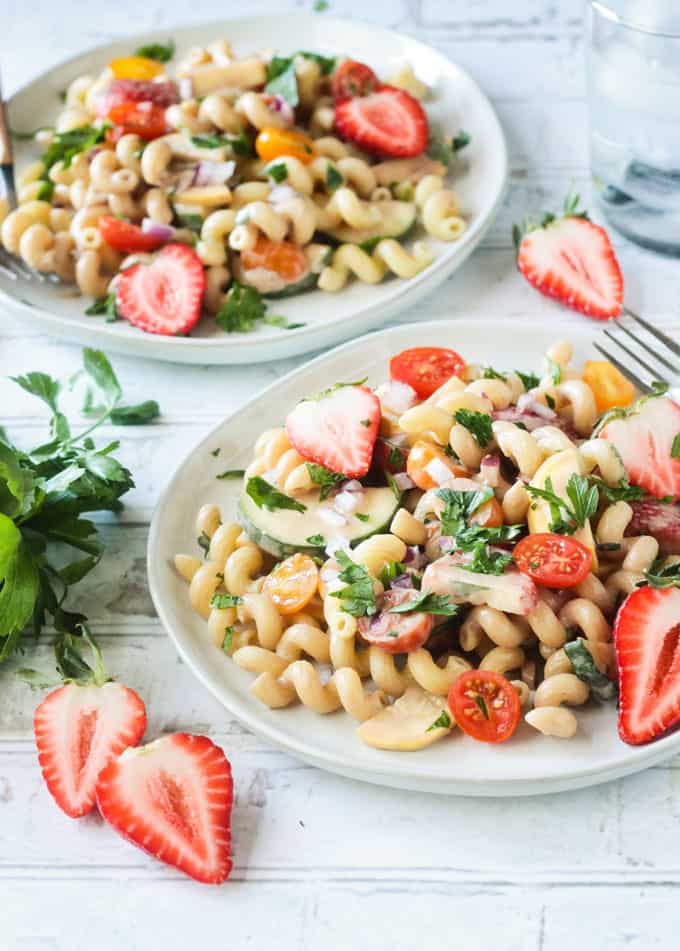 Vibrant fresh vegetables and strawberries in a summer pasta salad.