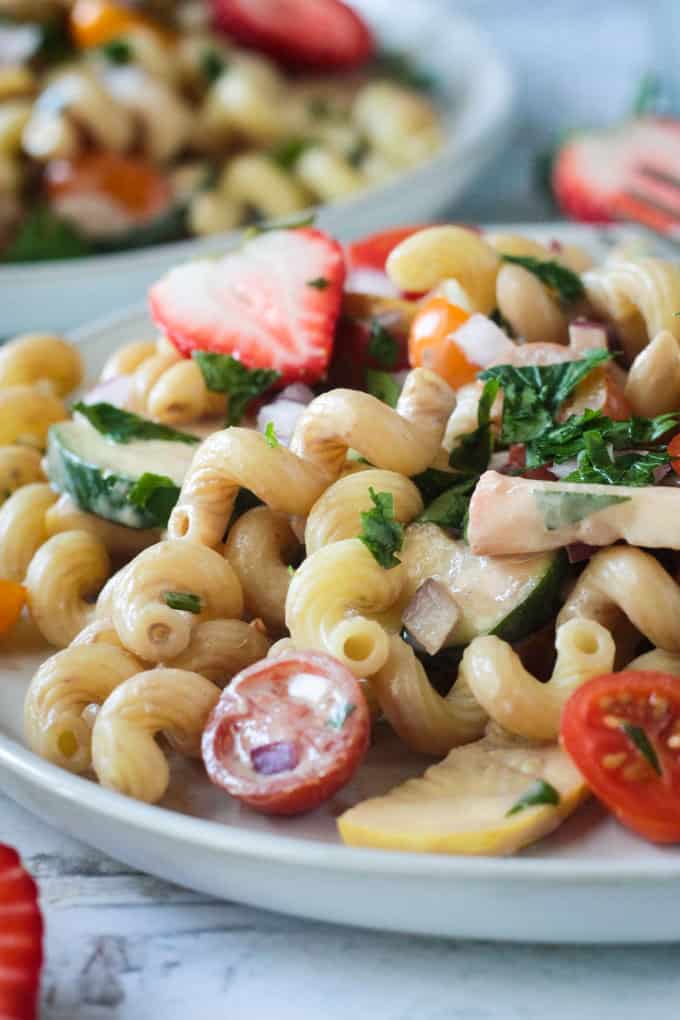 Close up of curly noodles in a bowl of summer pasta salad with creamy balsamic dressing.