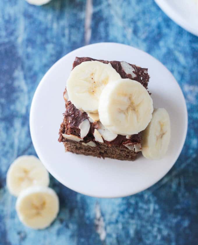 Overhead view of a slice of banana bread cake topped with fresh sliced bananas.