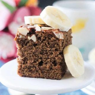 Square slice of banana bread cake toped with fresh banana slices and slivered almonds.