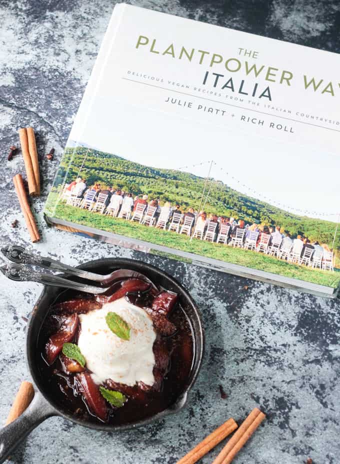 A skillet of poached nectarines next to The PlantPower Way: Italia Cookbook