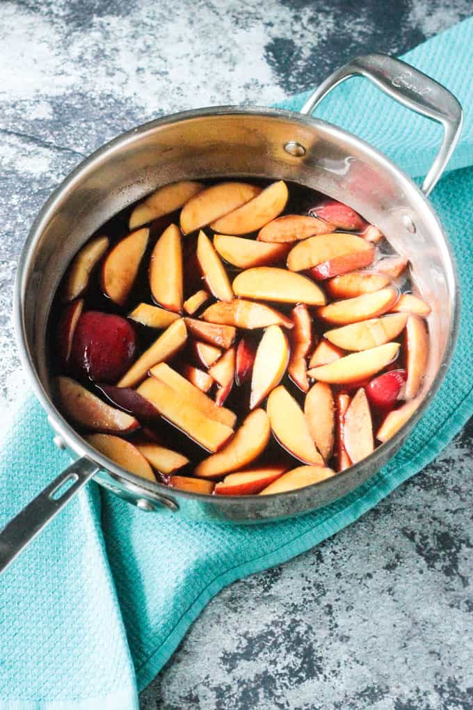 A large skillet of nectarines in a red wine sauce ready for poaching
